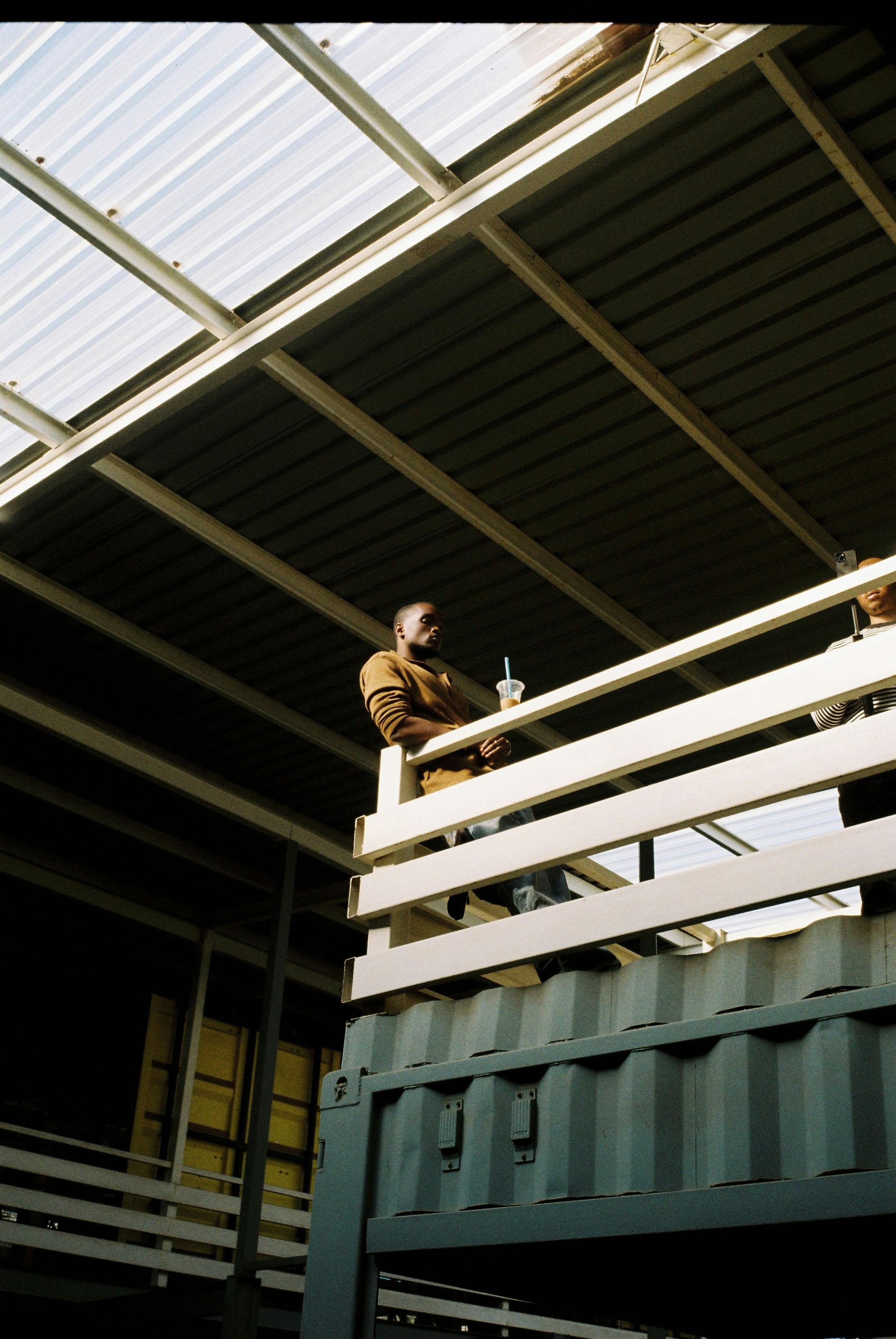 Casual man enjoying a drink on a modern industrial balcony, artistic vibe.