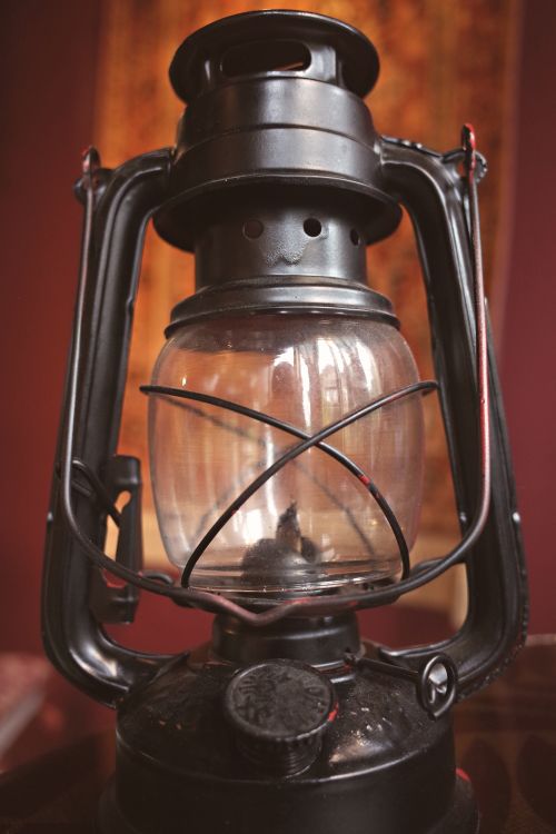 Free Close-up of a vintage oil lantern on a wooden table with a warm background Stock Photo