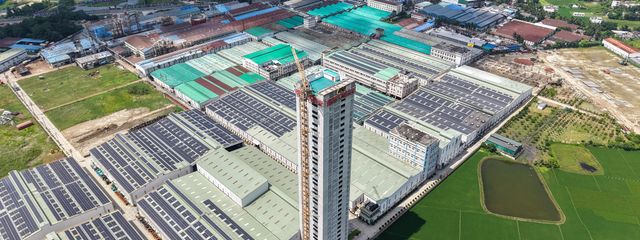 Aerial view of a large industrial factory complex and green fields.