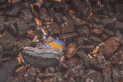 儿童的鞋子散落在香烟垃圾和岩石中，凸显了瑞士的污染问题