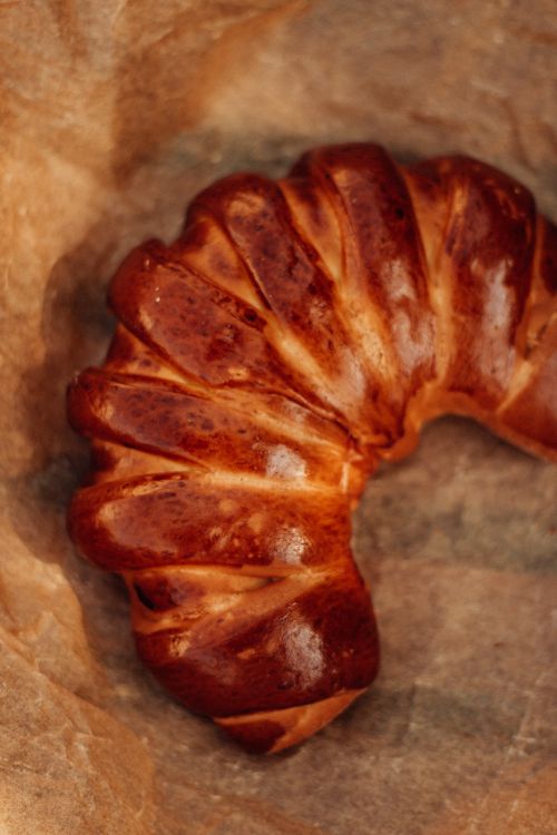 Free Close-up of golden crescent bread, freshly baked on parchment paper. Stock Photo