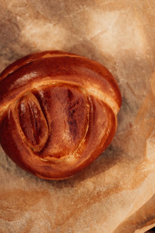 Free A beautifully baked sweet pastry with a golden crust, set on parchment paper, highlighting its artisanal texture. Stock Photo