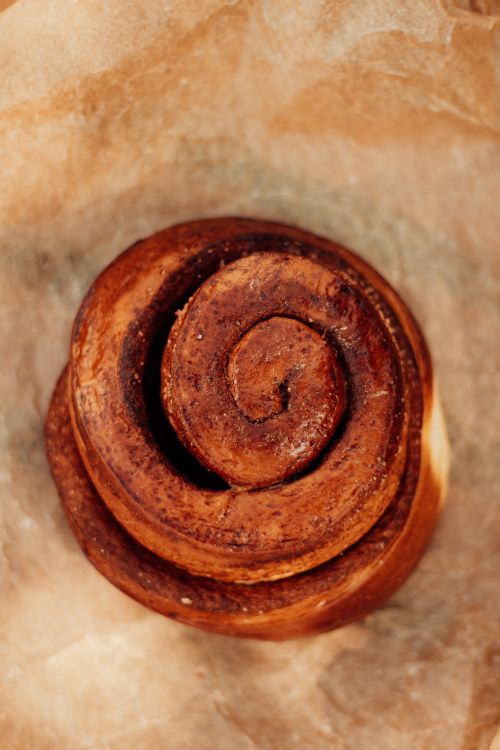 Free Freshly baked homemade cinnamon roll on parchment paper, top view Stock Photo