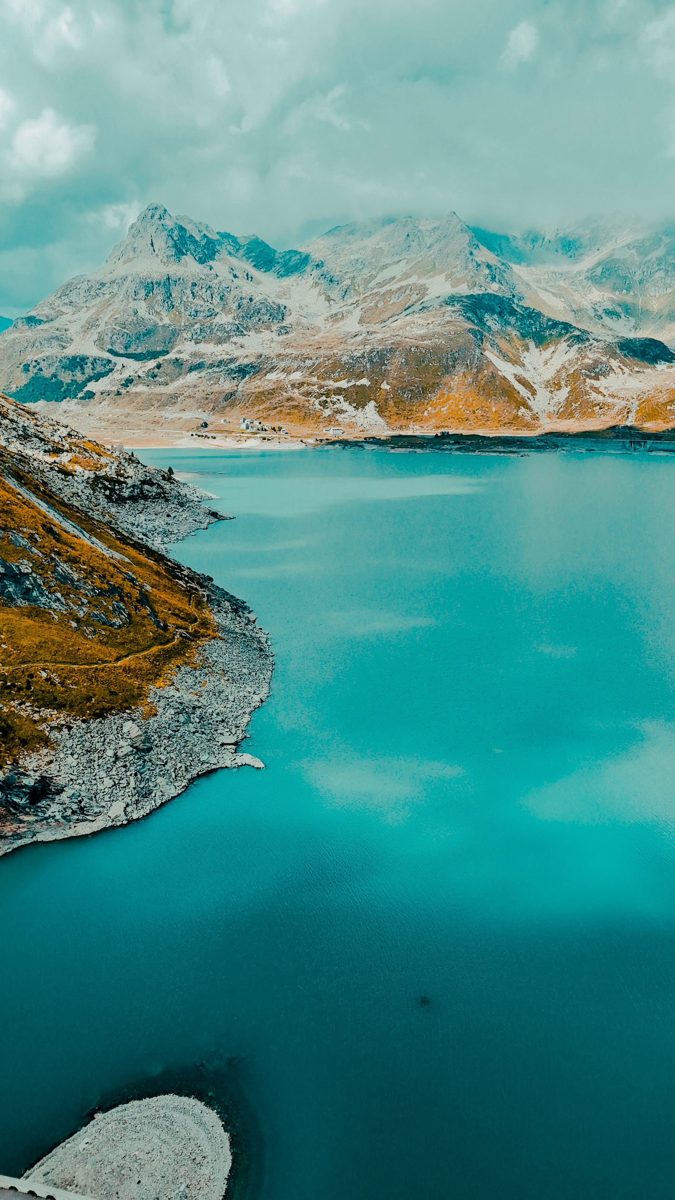 A stunning view of an alpine lake surrounded by mountains, captured from the air on a clear day.