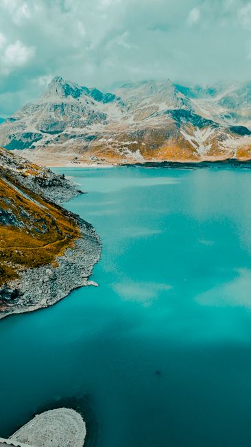 A stunning view of an alpine lake surrounded by mountains, captured from the air on a clear day.