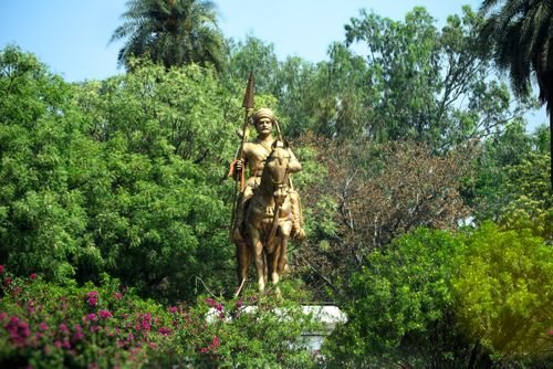 Free A stunning statue of a warrior on horseback surrounded by lush greenery in Agra, India. Stock Photo