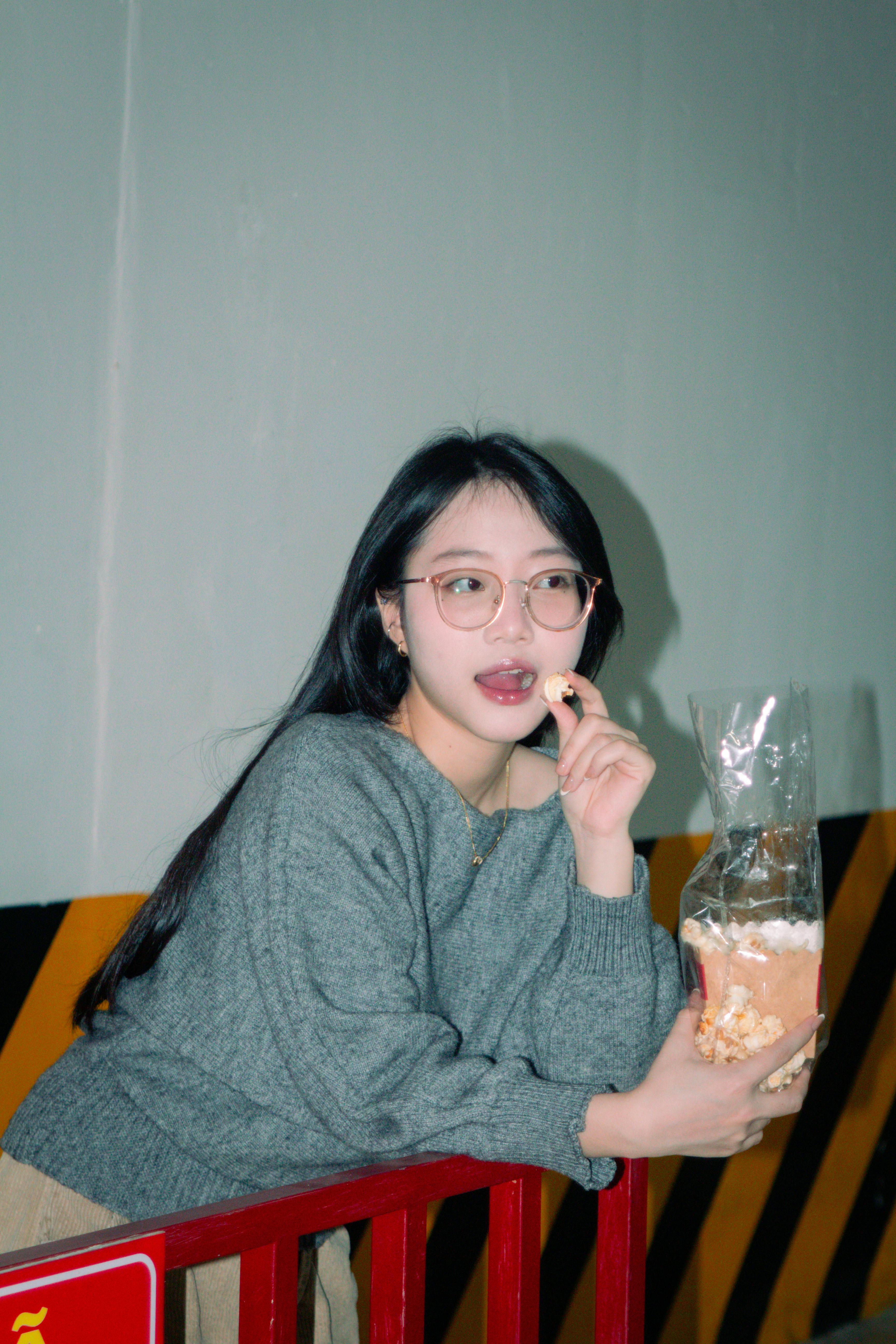 Gratuit Jeune femme savourant du pop-corn à l'intérieur, dans un cadre détendu et décontracté. Photos