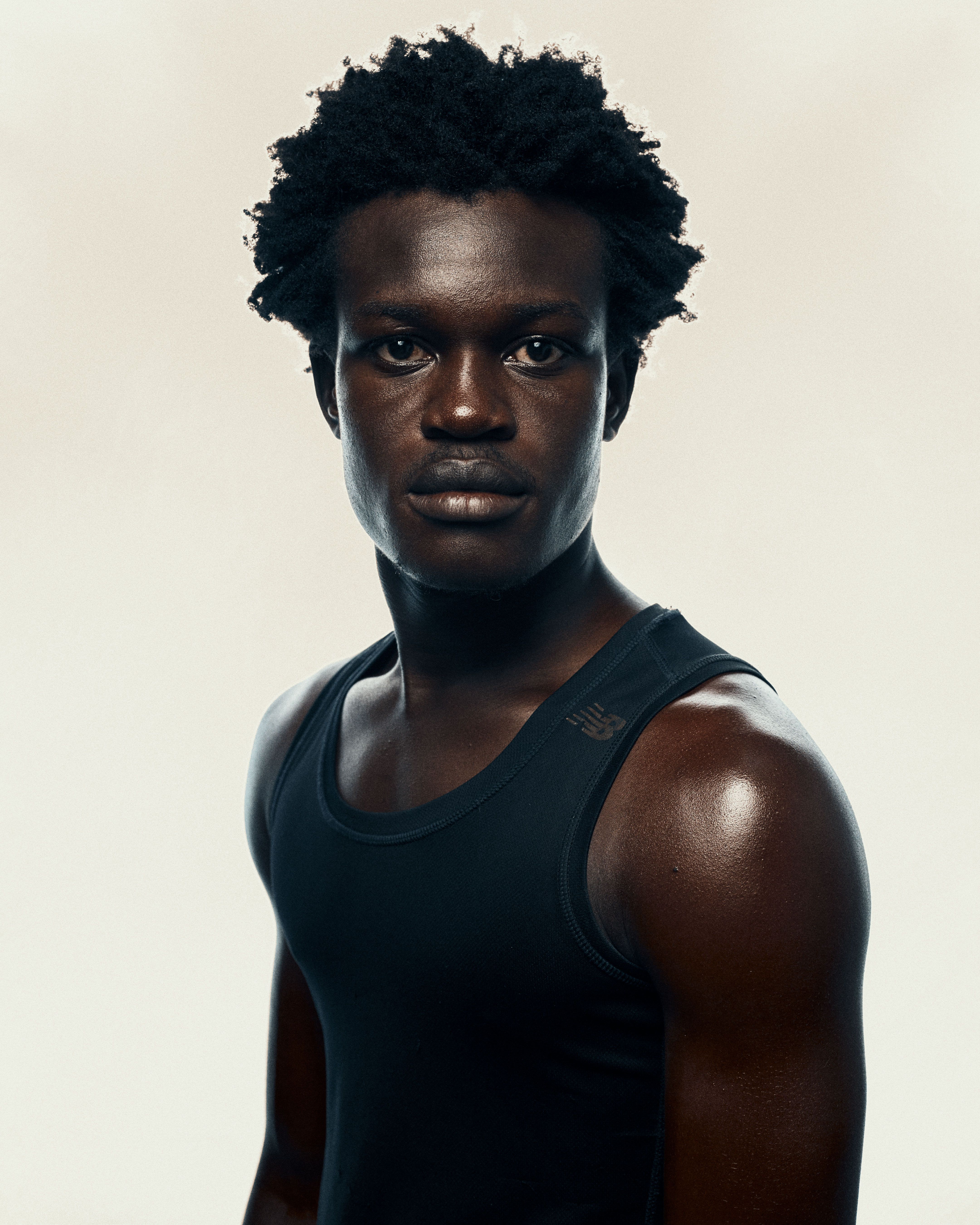 Powerful portrait of a young man in a black tank top, showcasing bold Afrocentric style.
