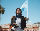 A man in historical costume poses proudly in front of the iconic Casa Rosada in Buenos Aires, Argentina.