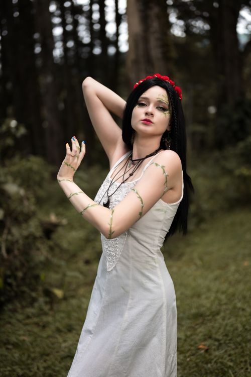 Free Ethereal portrait of a woman in a forest wearing a white dress and red floral headpiece. Stock Photo