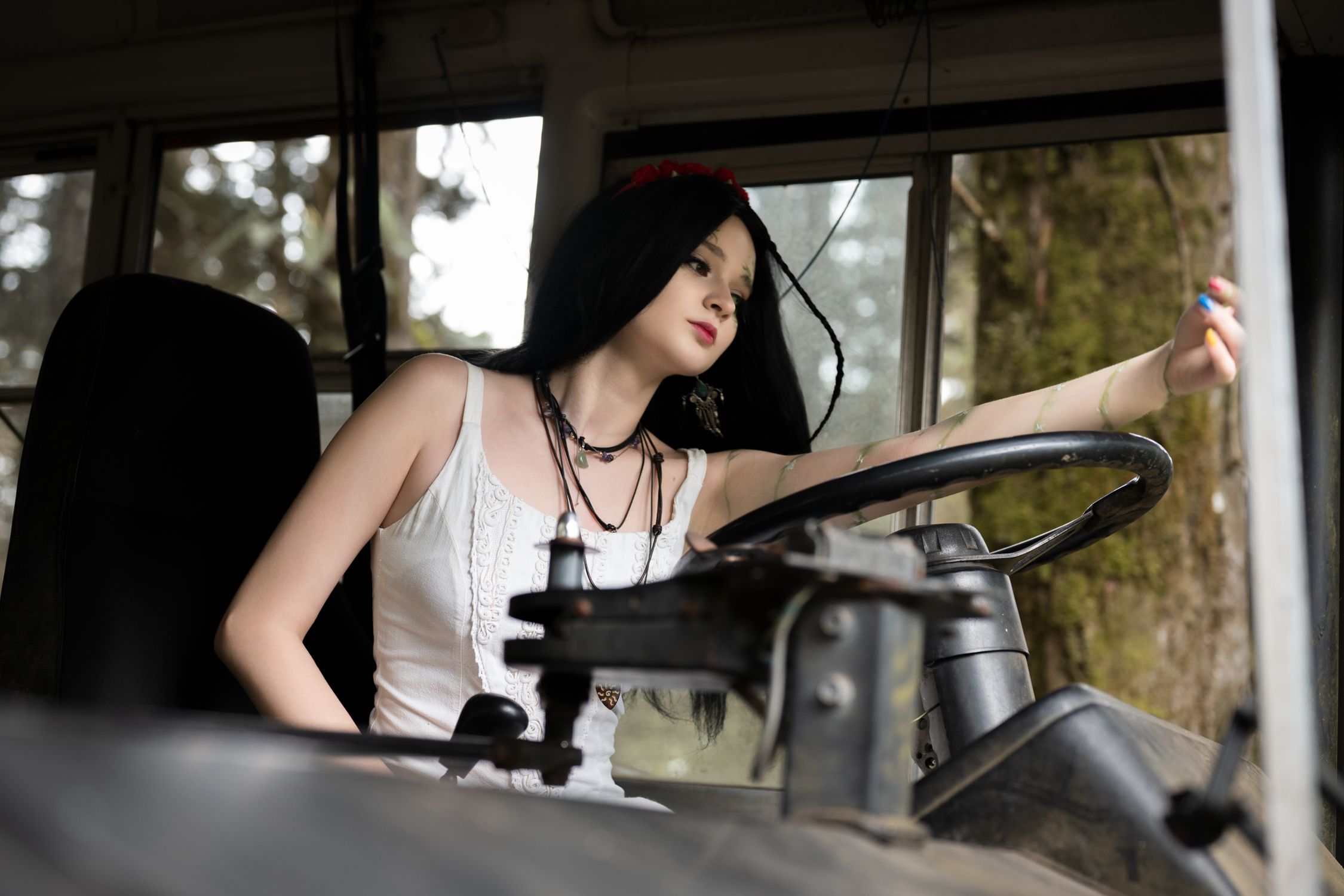Artistic portrait of a young woman driving an old bus amidst lush greenery