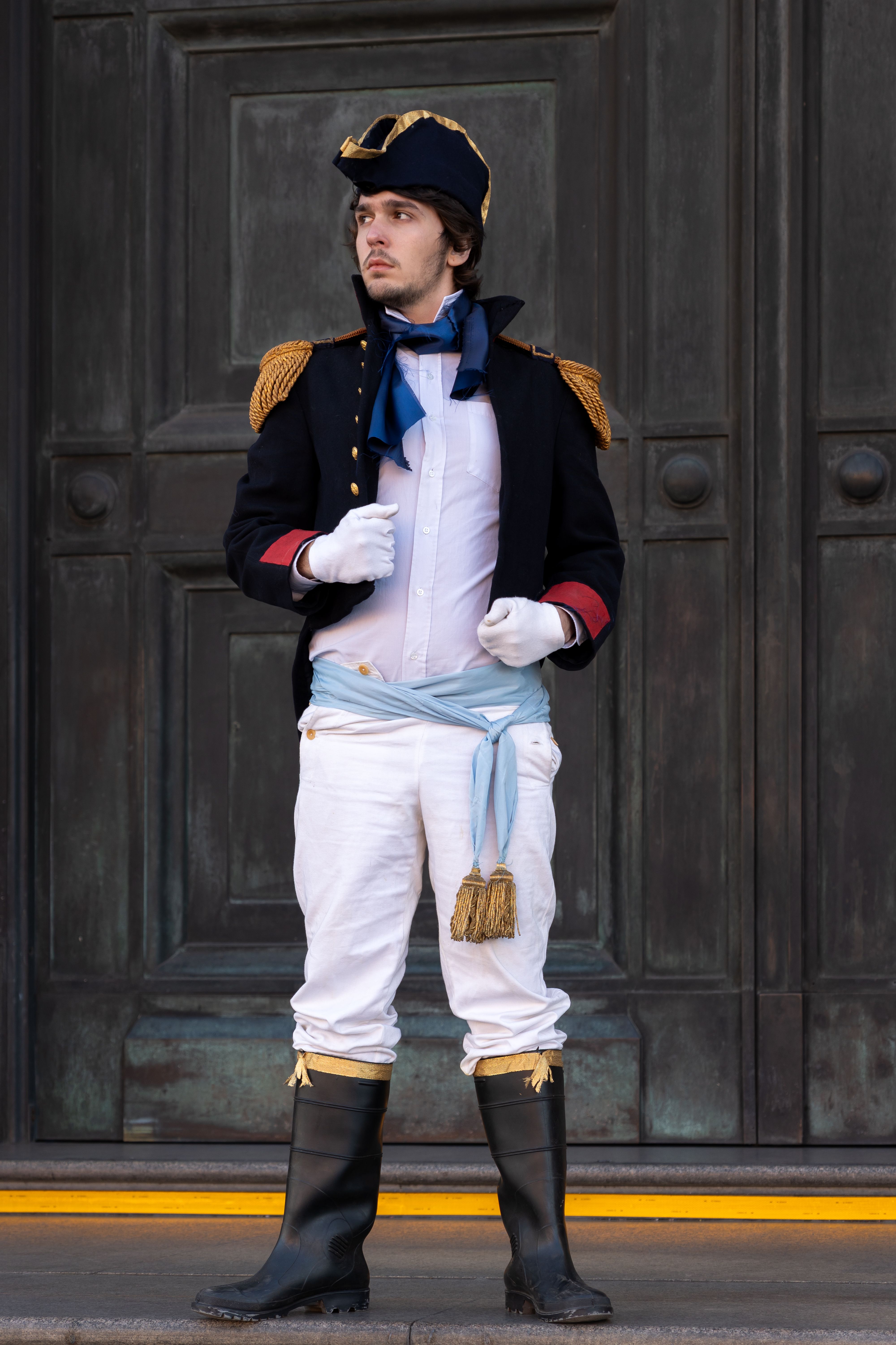 Man in historic military costume posing in front of a grand door in Buenos Aires, Argentina.