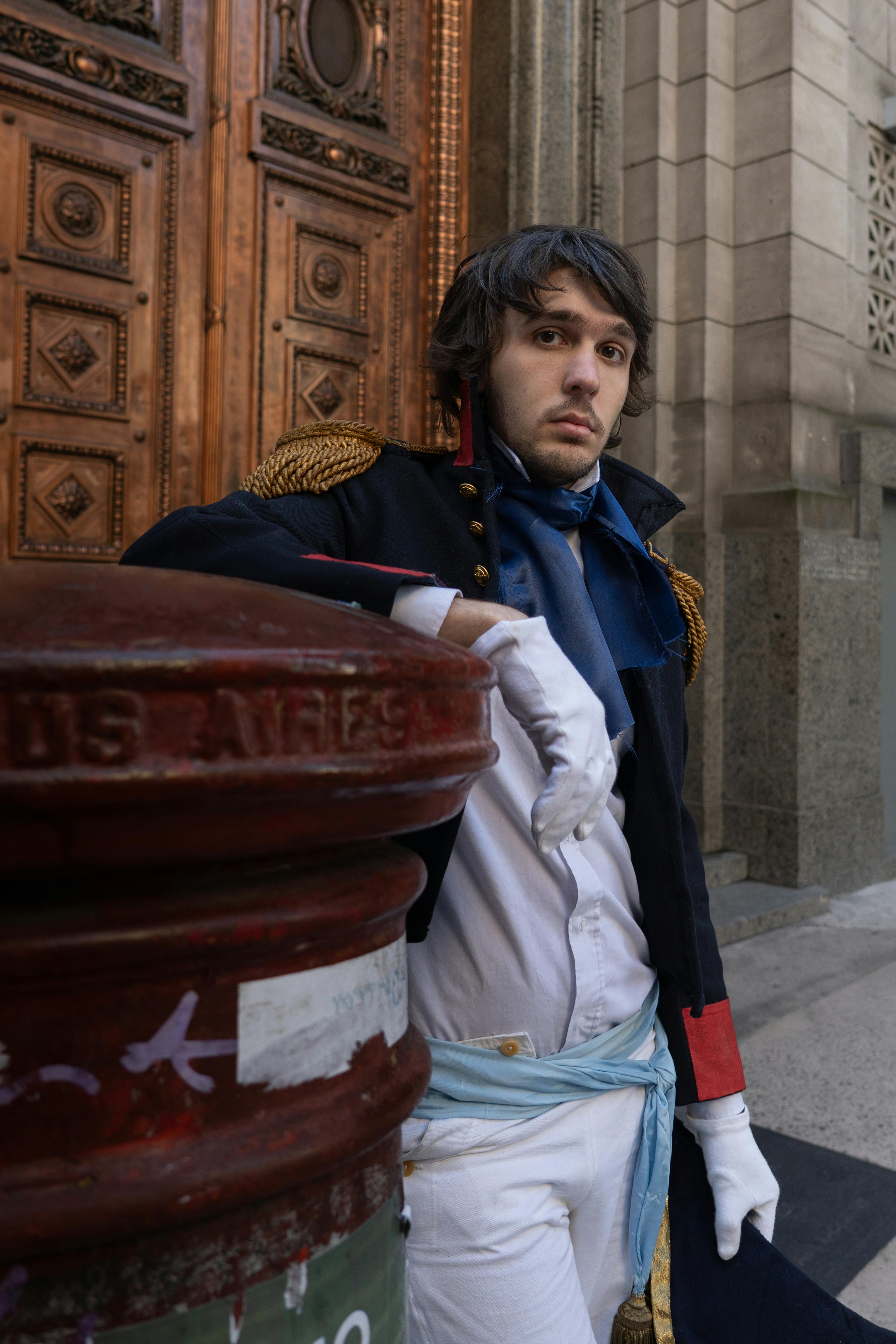 A man in historical costume by ornate wooden door in Buenos Aires.