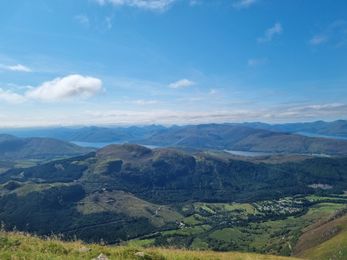 Panoramic view of Scottish Highland green hills under blue sky