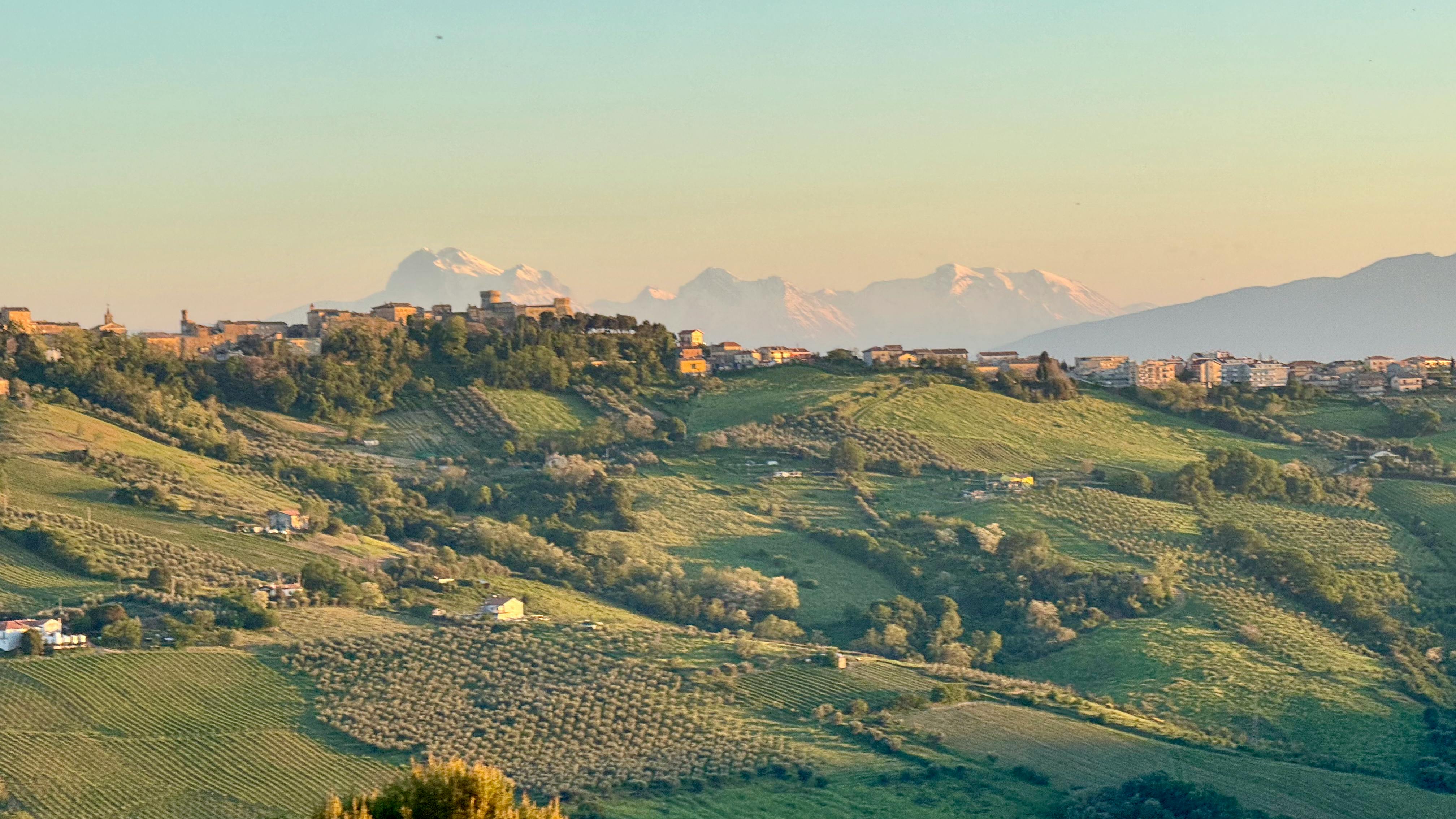 Colline marchigiane con borgo e tramonto dorato sulla valle