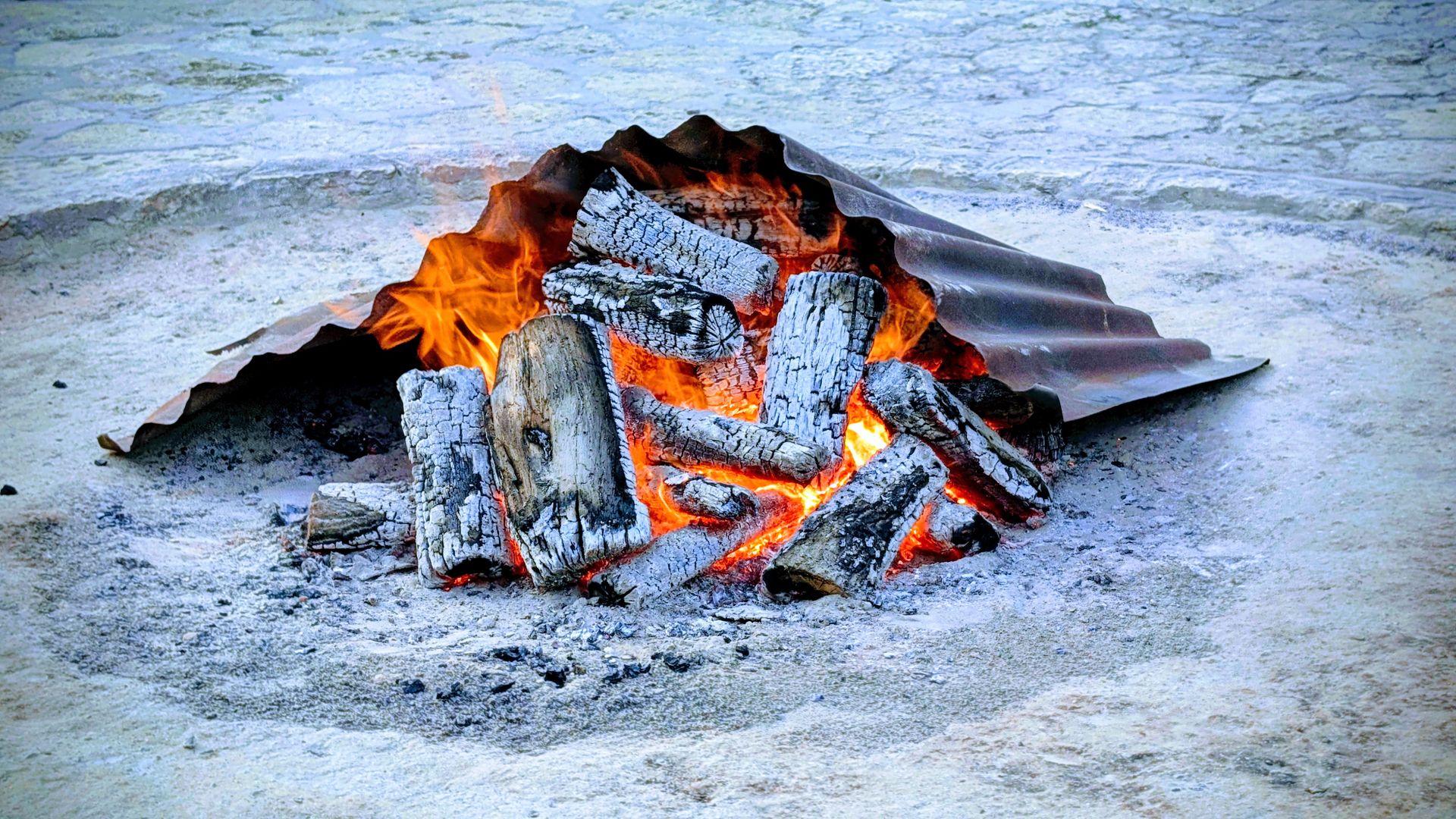 A close-up of a traditional fire pit with wood burning and glowing embers in Varna, Bulgaria.