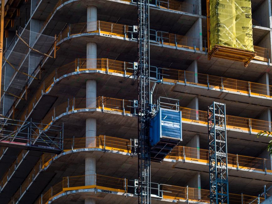 Detailed view of a high-rise building construction featuring a crane and multi-level scaffolding.