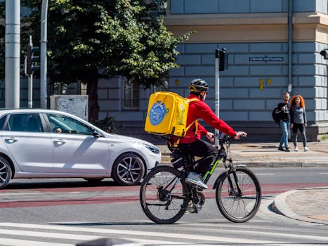 Bicycle courier with delivery backpack riding through city street in daylight.