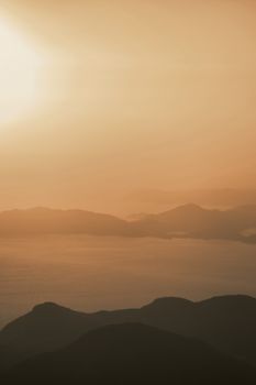 Peaceful mountain landscape with a golden sunset casting an enchanting glow over the horizon.