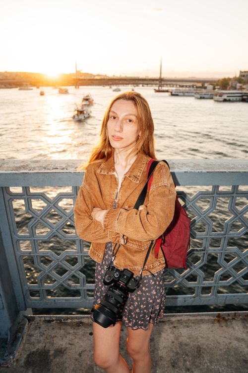Free Woman photographer on Galata Bridge, İstanbul, capturing stunning sunset view. Stock Photo