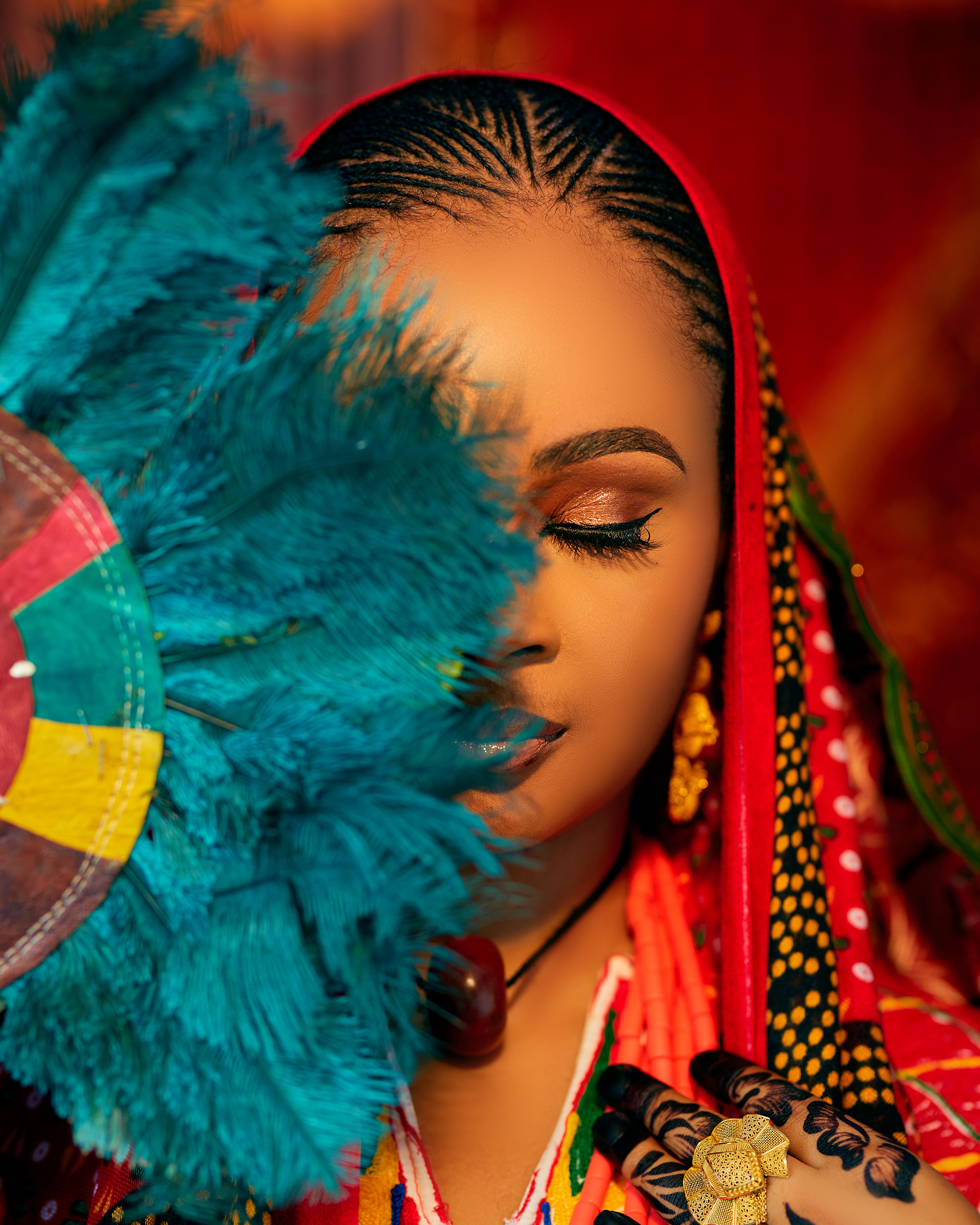 Close-up portrait of a woman in traditional attire, holding a vibrant fan.