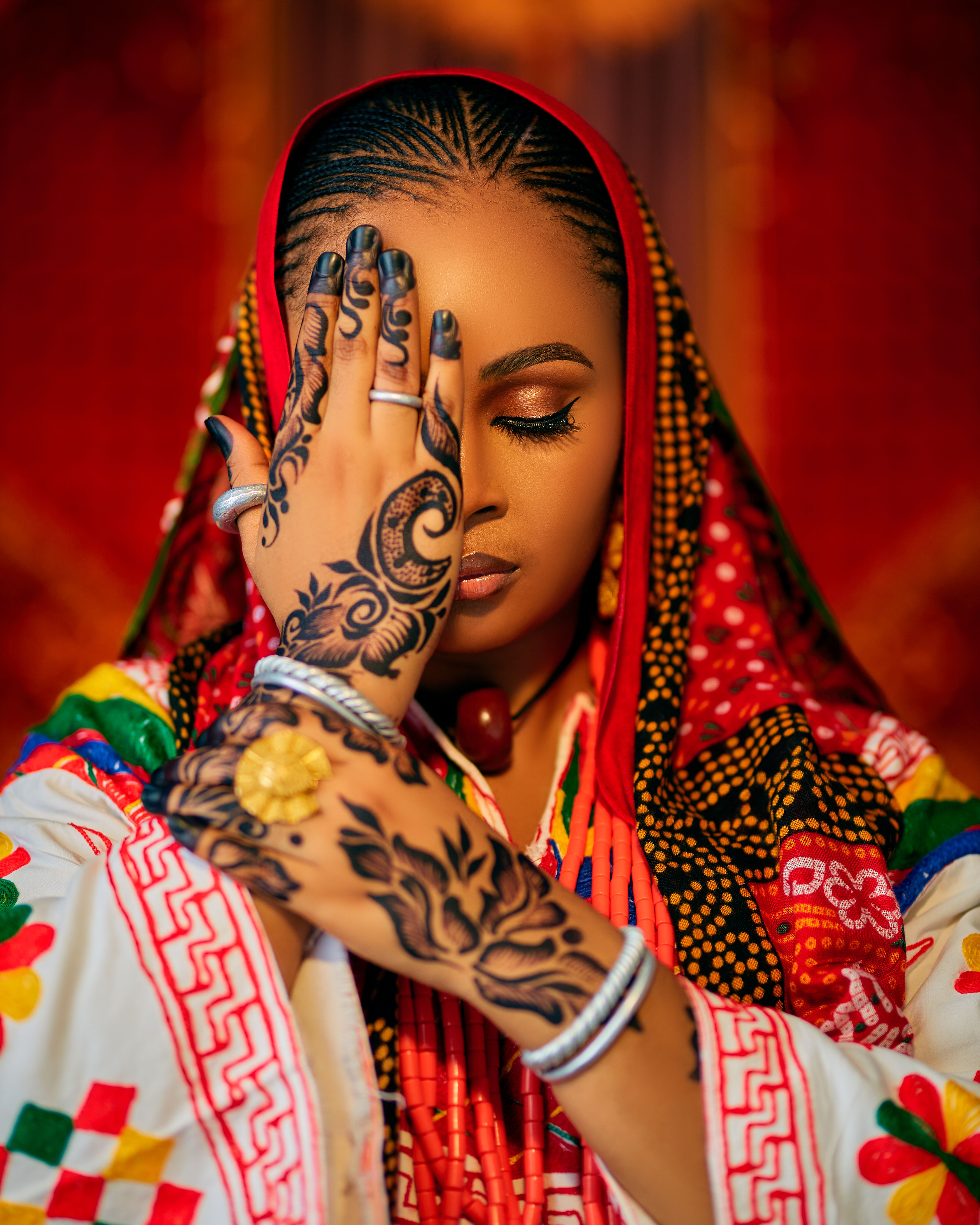Woman in vibrant traditional dress with intricate henna designs on hand.