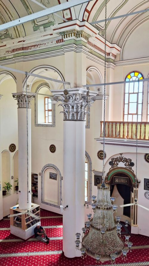 Free A stunning view of a mosque's interior showcasing ornate columns and a grand chandelier. Stock Photo