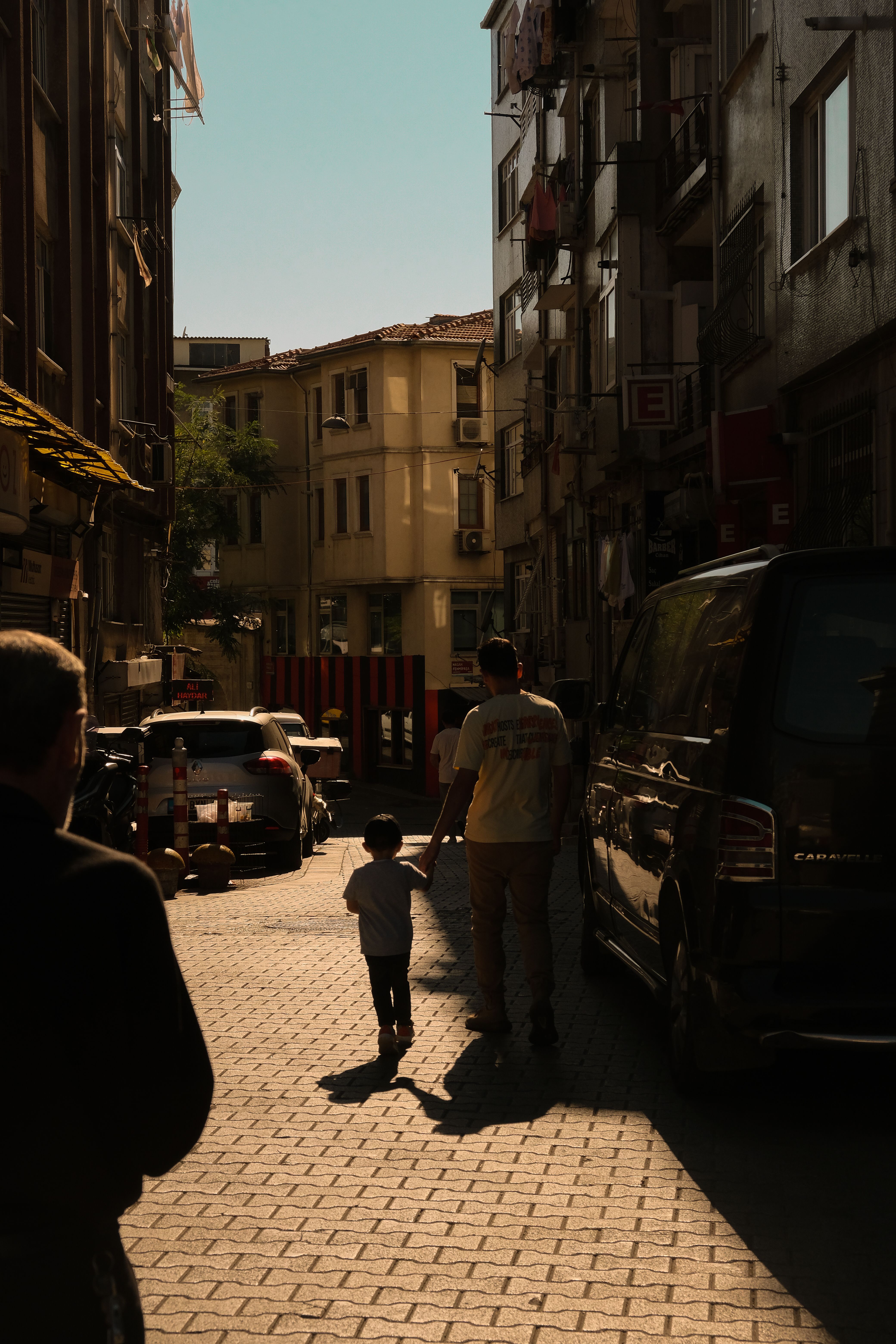 A father and son walking together on a sunlit street in Istanbul, captured during sunset.