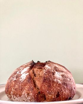 A freshly baked rustic sourdough bread with a golden crust on a plate.