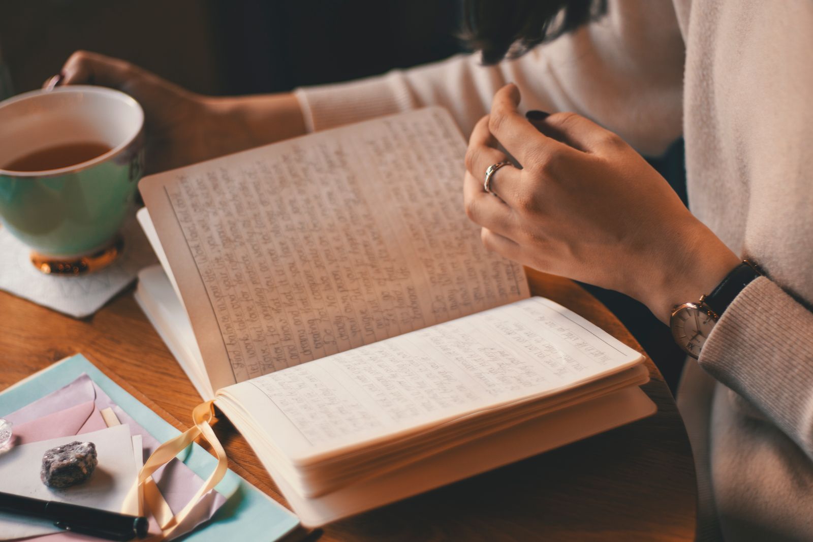 A person journaling with a cup of tea in soft morning light
