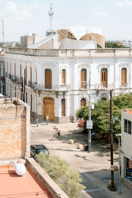 A historic white building with arched windows on a sunny day in an urban environment.