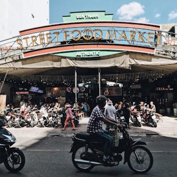 Bustling street food market scene in Ho Chi Minh City, with motorcycles and local vendors.