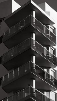 Striking black and white photo of a modern high-rise with glass balconies, showcasing urban architecture.