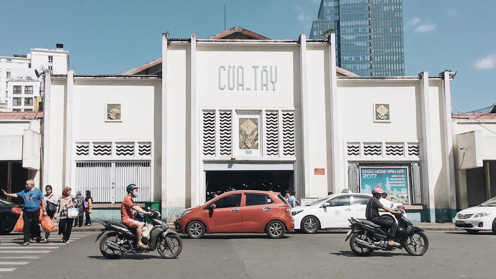 Motorbikes and pedestrians in front of a busy market in Hồ Chí Minh City, Vietnam.