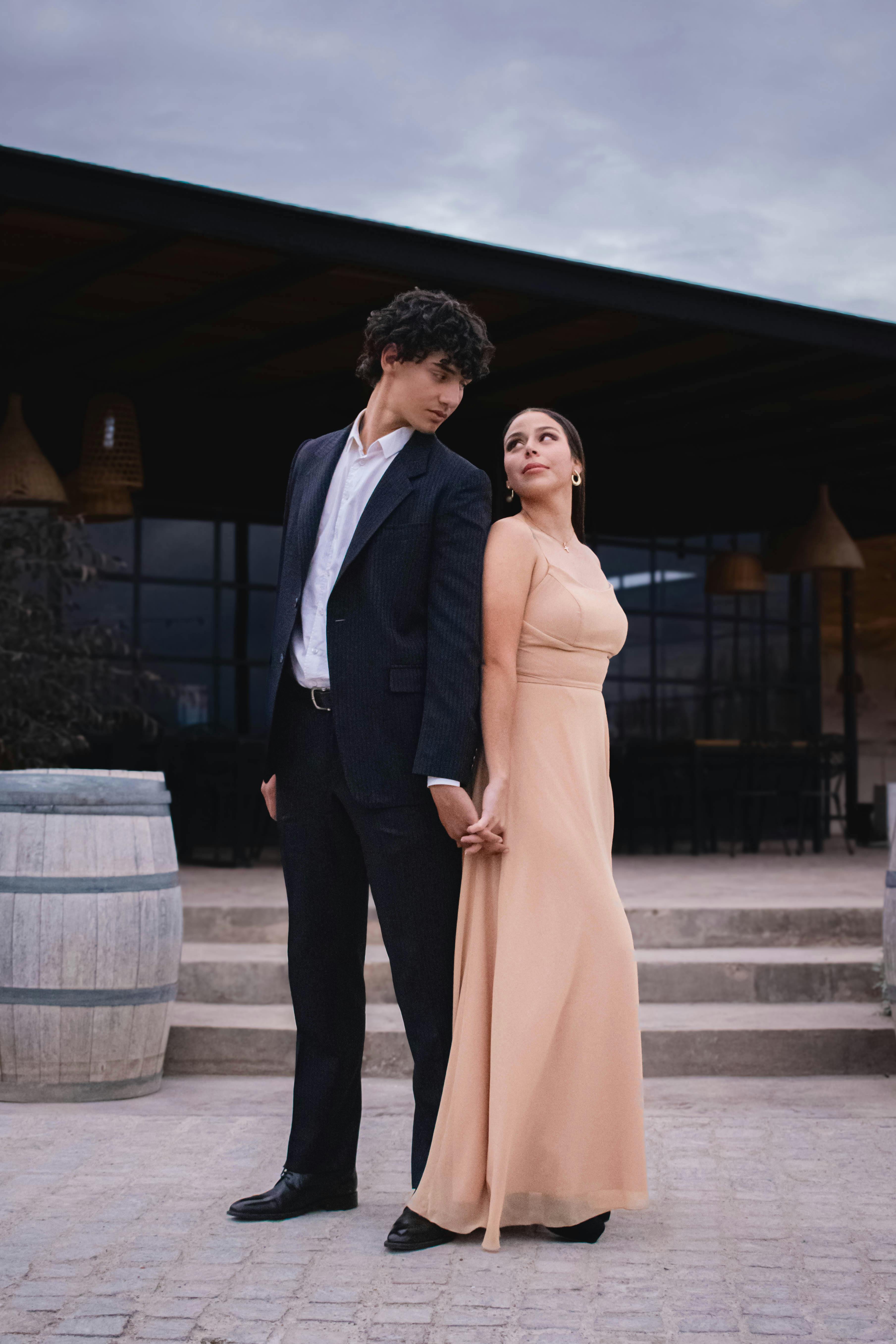 Sophisticated couple in formal wear holding hands outdoors, creating a romantic atmosphere.