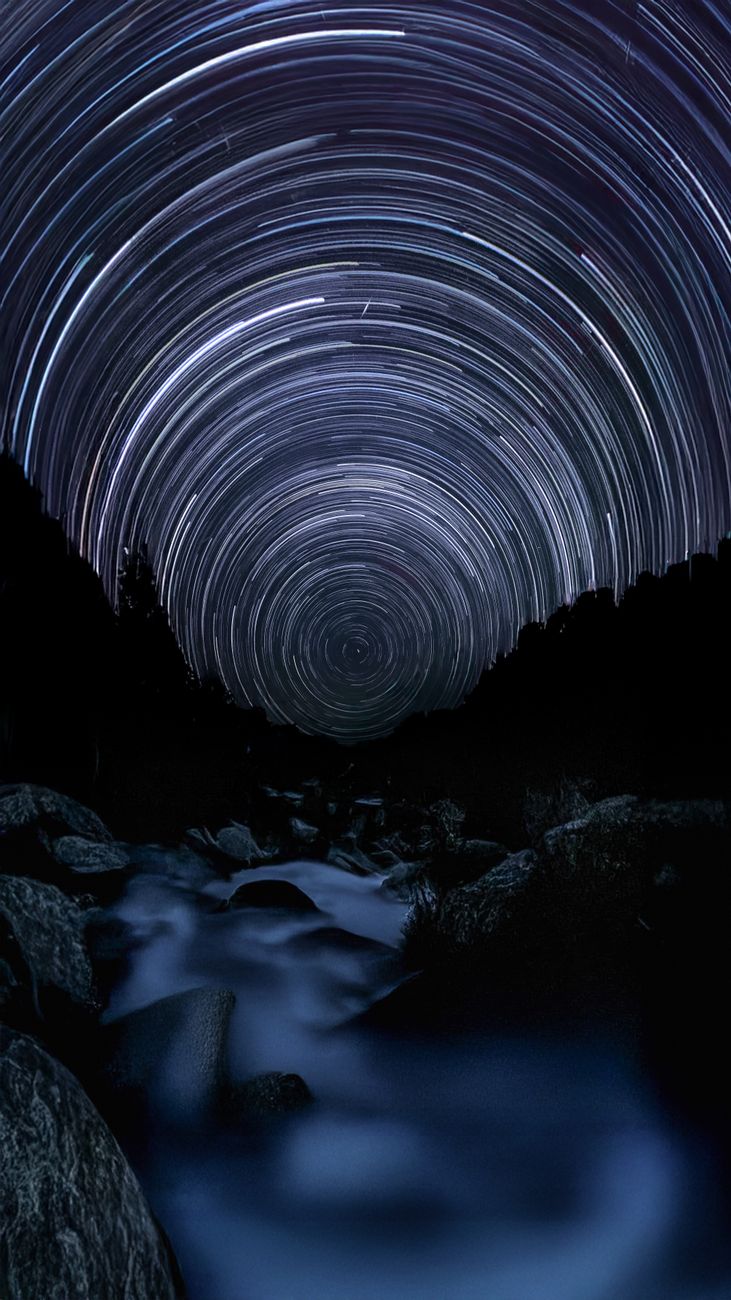 Long exposure captures stunning star trails above a tranquil river in the forest. Perfect for astronomy and nature enthusiast