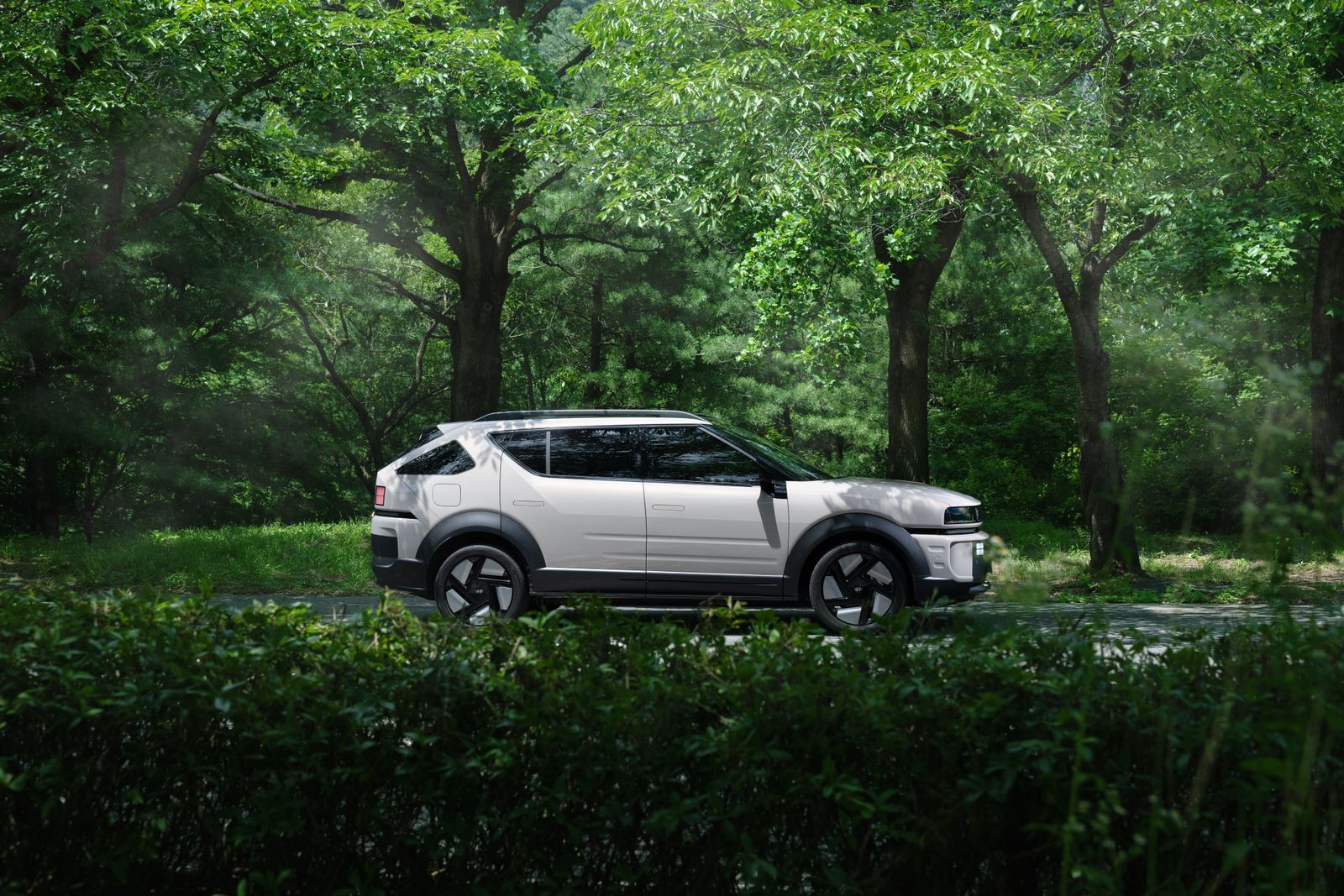 White adventure SUV in side profile on a tree-lined track