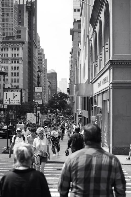 Free A lively street scene in New York City featuring busy pedestrians among towering buildings in black and white. Stock Photo