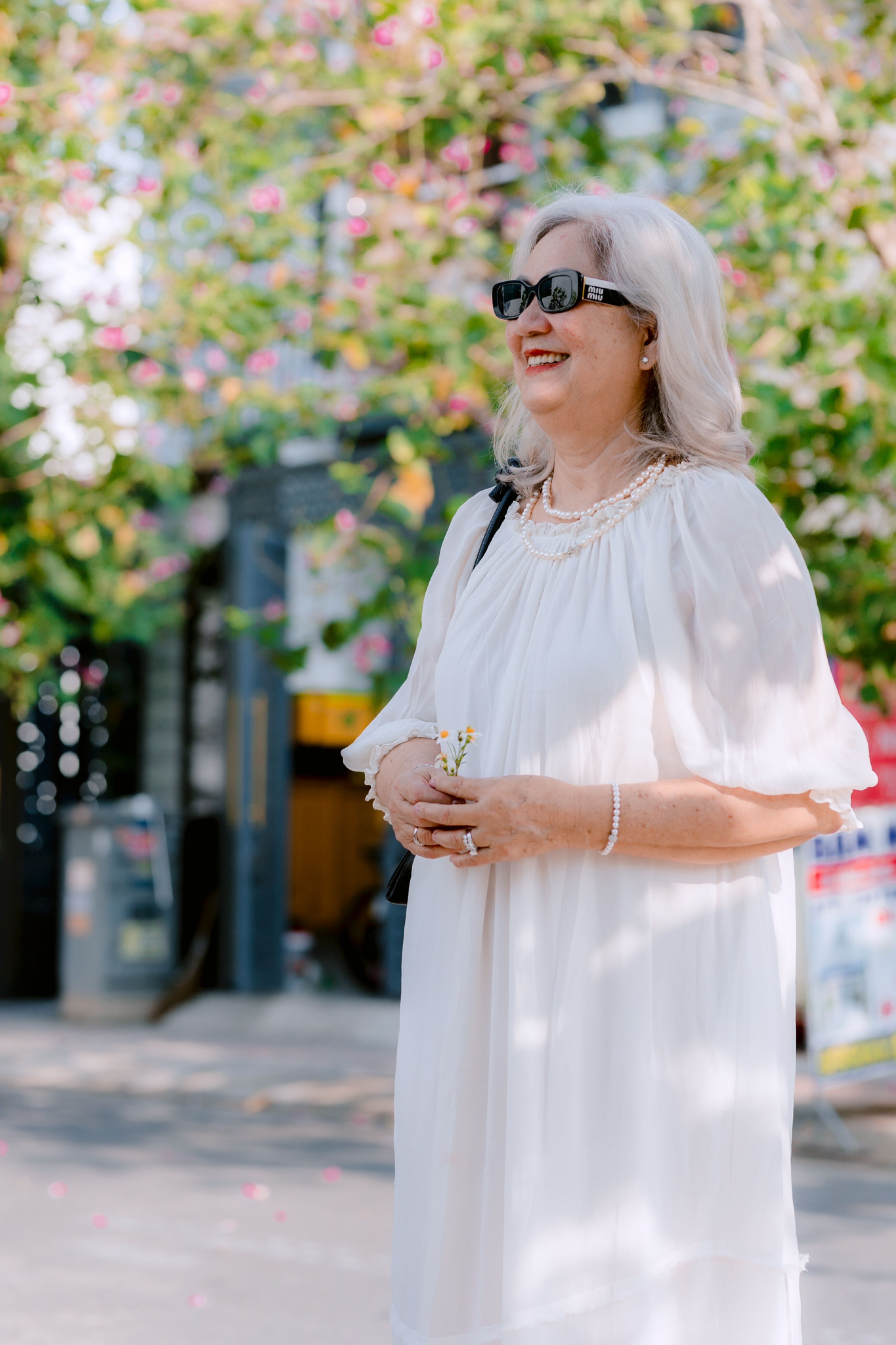 An elegant older woman wearing a kaftan dress with gold accessories at a resort