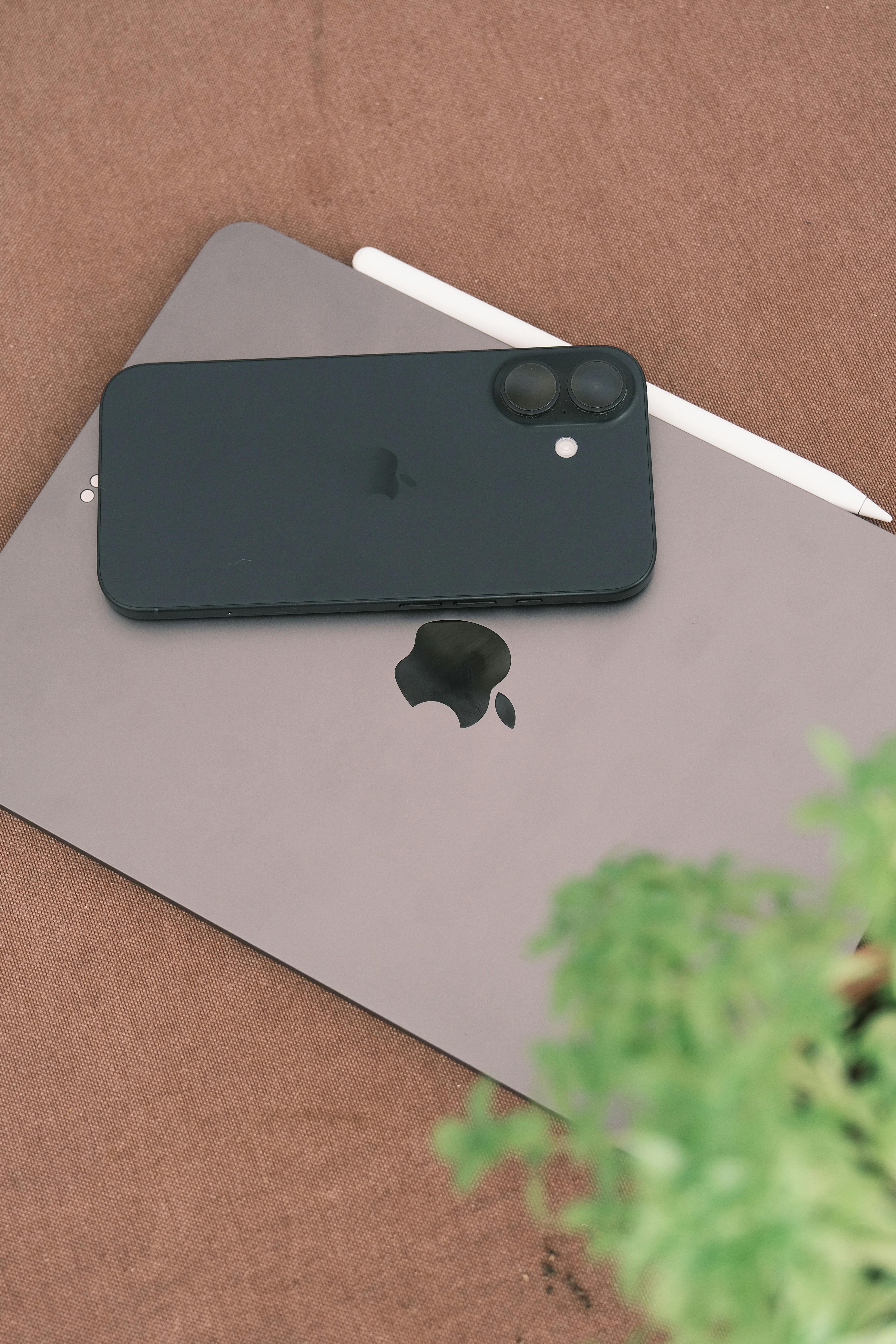 Gratis Ponsel pintar dan tablet berwarna hitam di atas meja berwarna coklat dengan tanaman hijau. Foto Stok