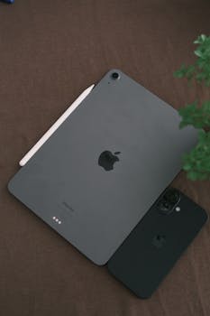 Sleek black tablet and smartphone on a brown surface with a pen, creating a minimalist tech vibe.