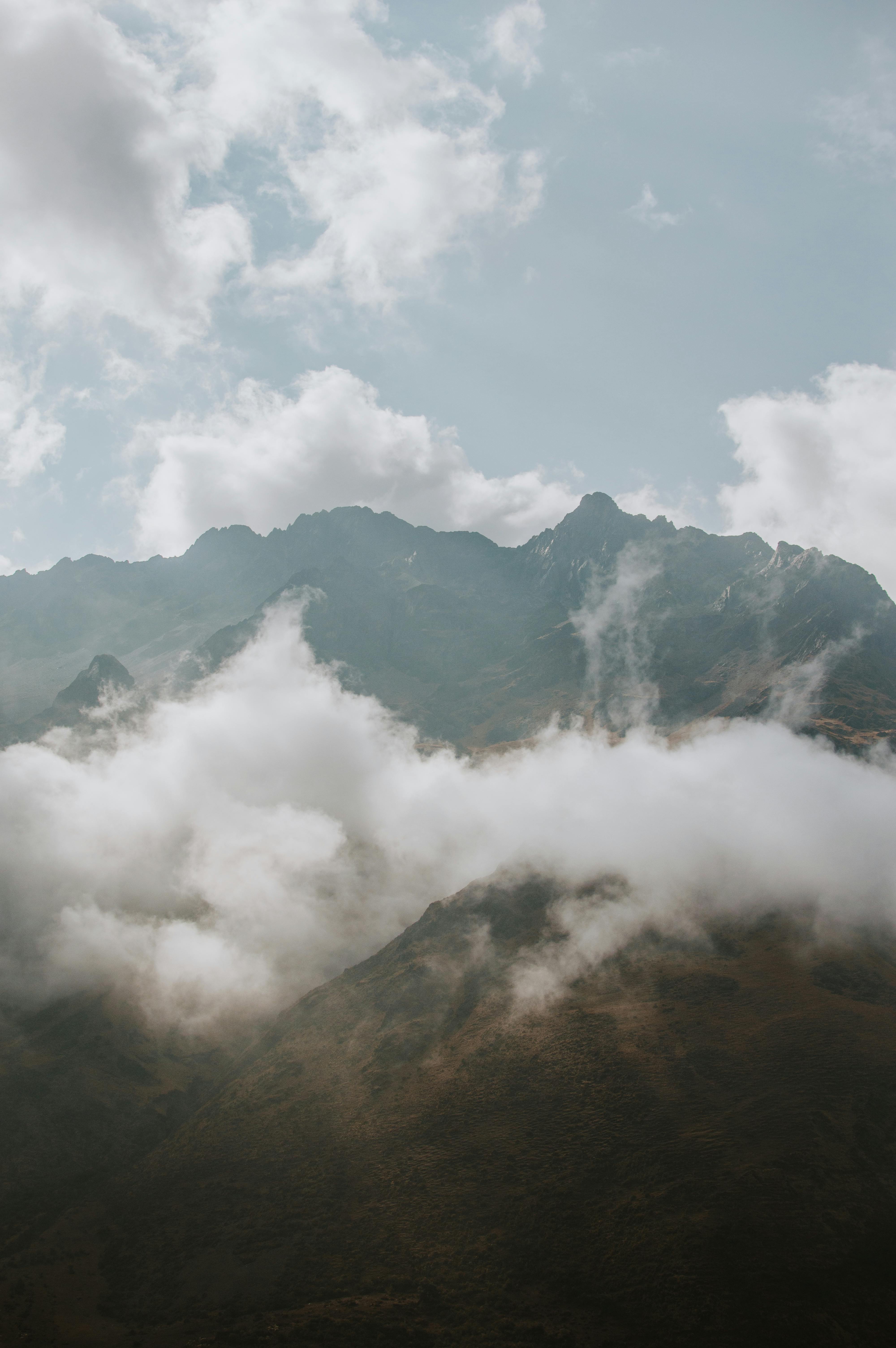 Clouds envelop the scenic peaks of the Andean mountains near Cuzco, Peru, creating a mystical atmosphere.