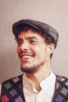 一位戴着复古帽子、身穿色彩缤纷拼凑背心的微笑男子的肖像