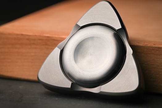 Detailed image of a sleek triangular metal fidget spinner on a wooden surface.