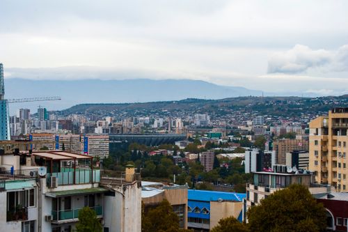 Free A vibrant aerial view of Tbilisi cityscape with modern and historical architecture under cloudy skies. Stock Photo