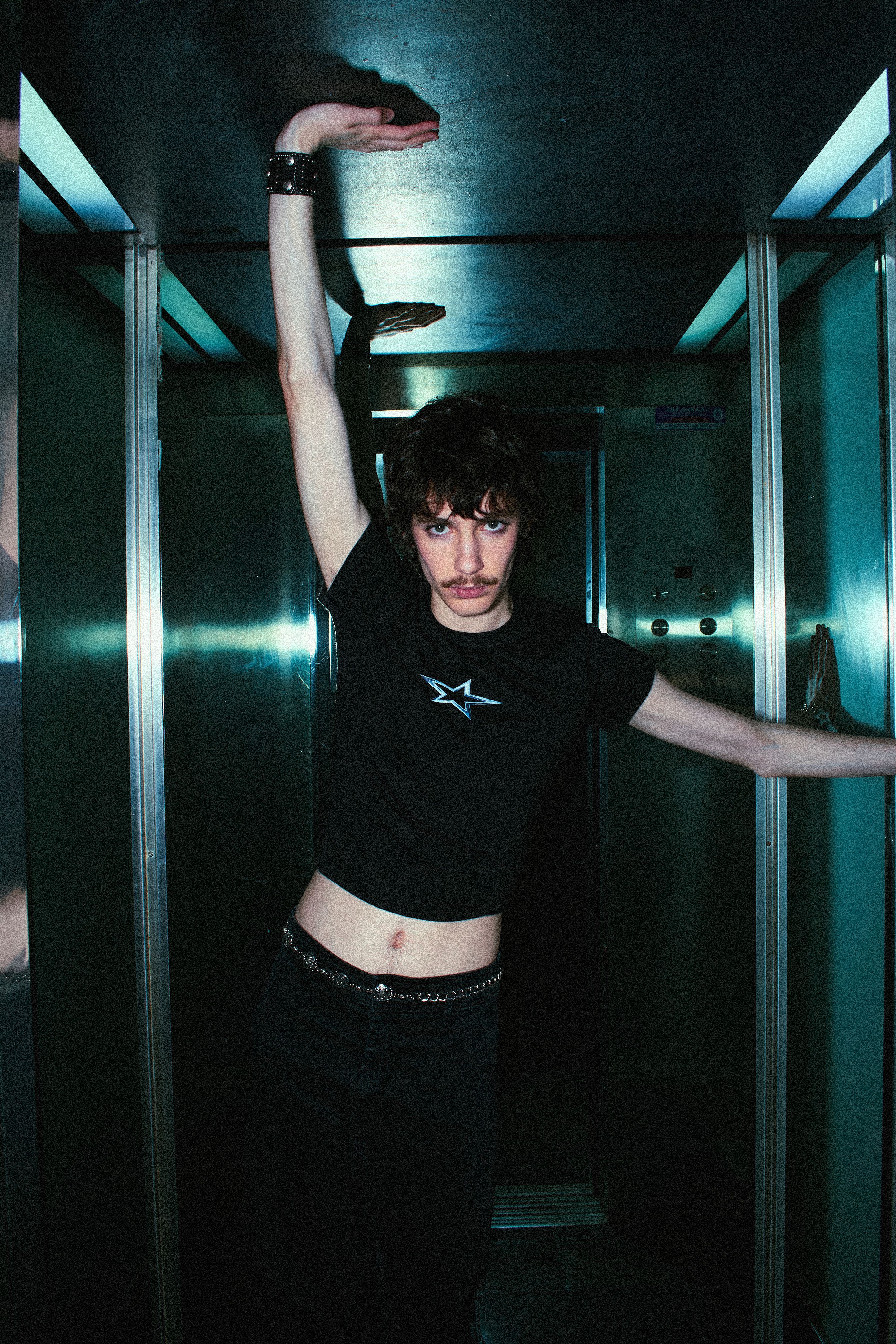 Fashionable young man posing confidently in an elevator with dramatic lighting.