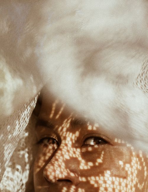A close-up shot capturing artistic shadow patterns on a woman's face in natural light.