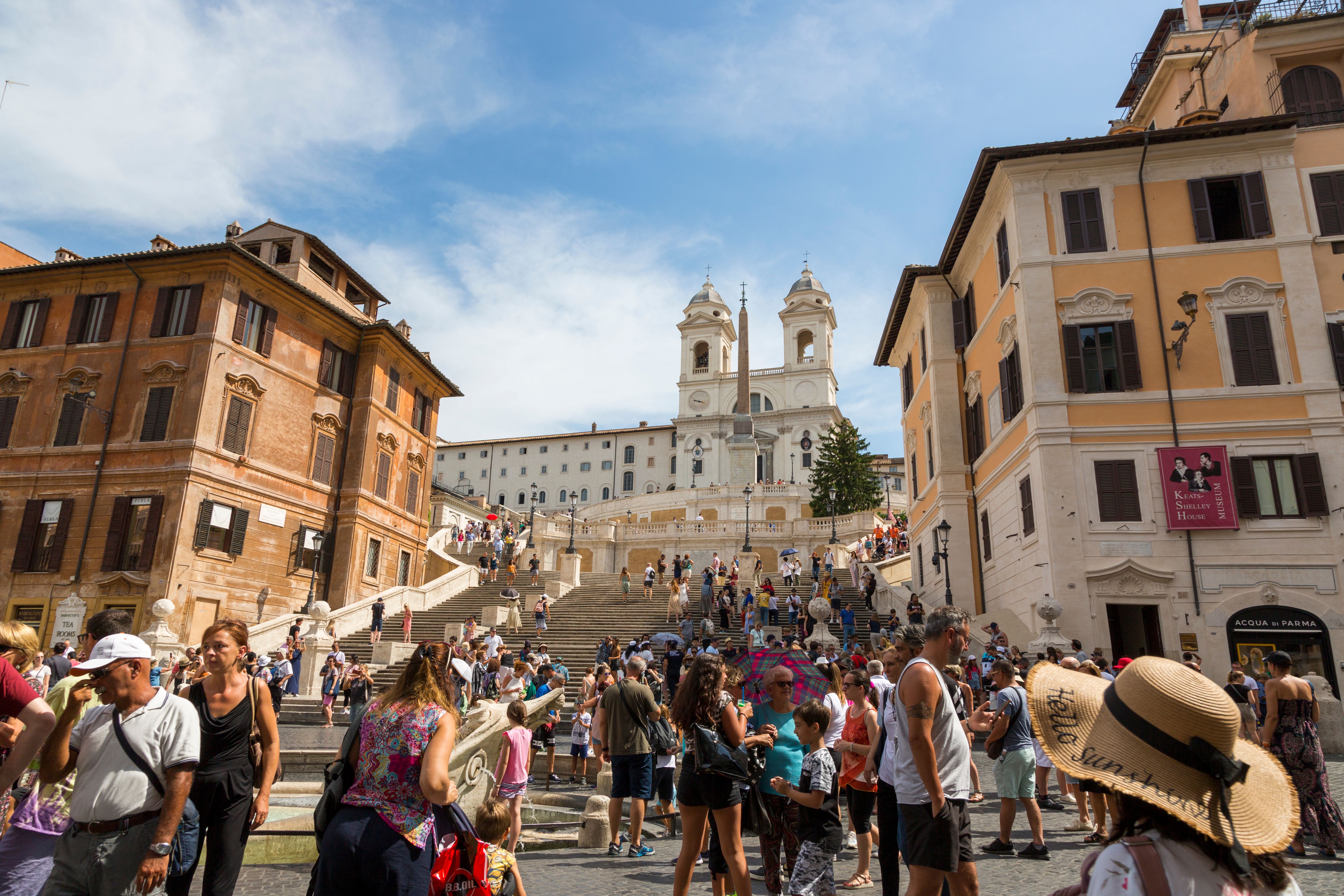 Crowded view of the Spanish Steps in Rome with people enjoying a sunny day.