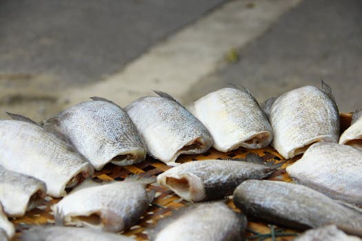 Close-up of dried fish arranged on a wicker tray outdoors.
