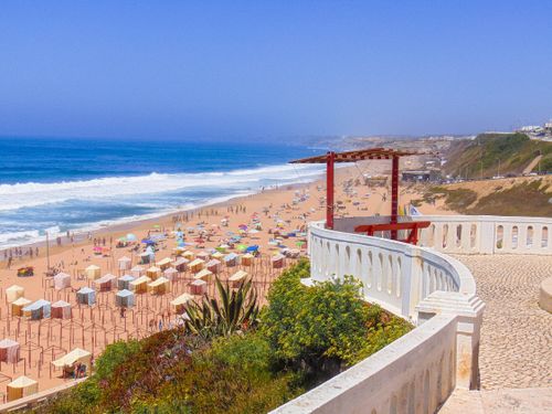 Free Vibrant beach scene in Silveira, Lisbon with colorful umbrellas and ocean view. Stock Photo
